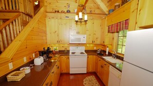 A cozy wooden cabin kitchen with a central stove, a microwave, and a sink.