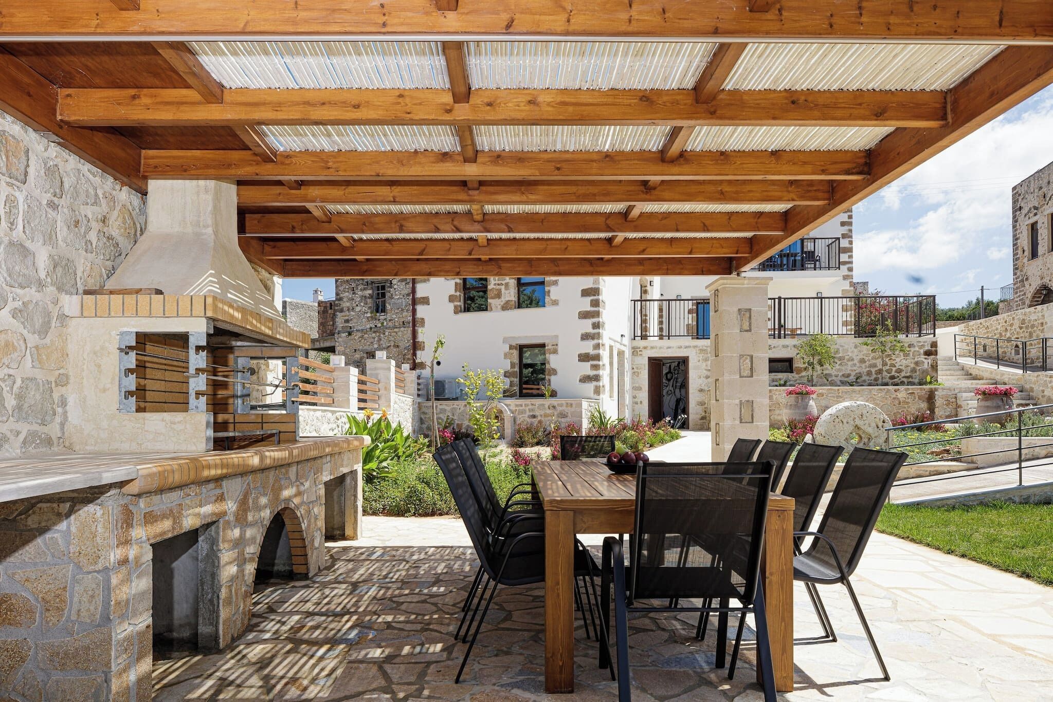 An outdoor patio with a stone fireplace, wooden table, and chairs.
