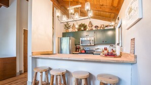 A kitchen with a wooden island, bar stools, and a hanging light fixture. - Sugar Pine Retreat - A/C & Pool Access (Camp Connell)