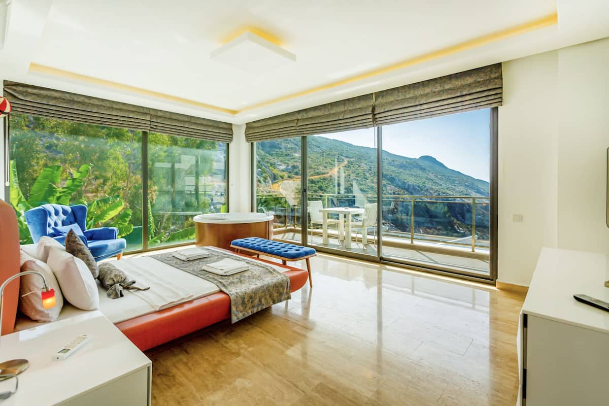 Un dormitorio moderno con una cama grande, una zona de estar y un balcón con vistas a la montaña.