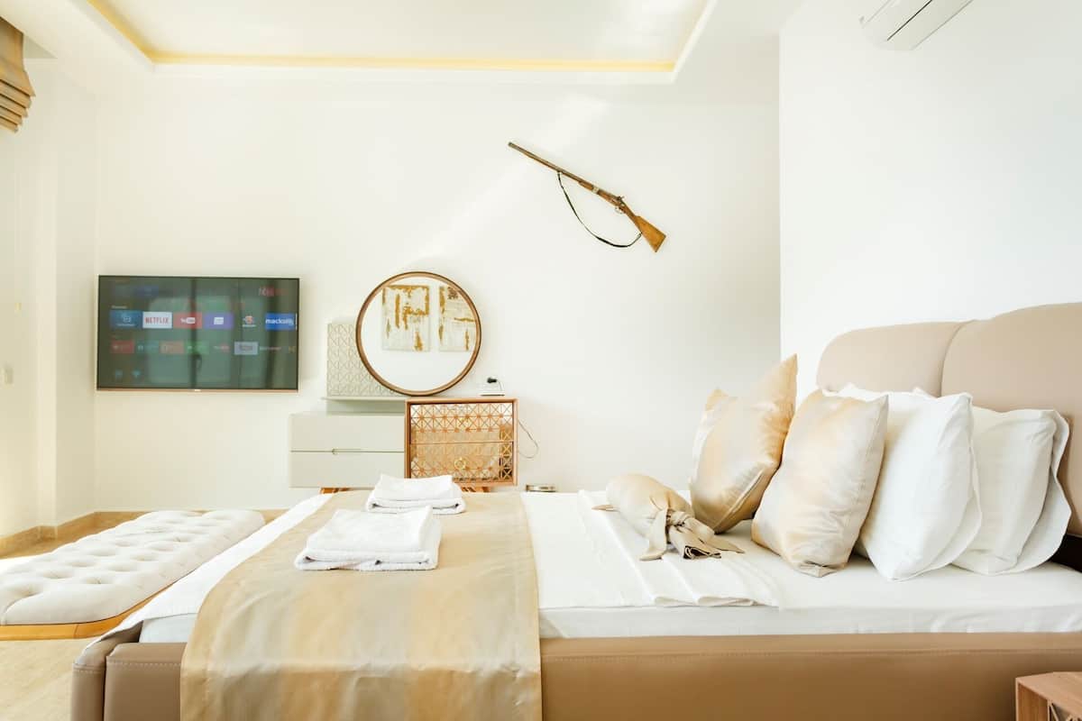Una habitación de hotel moderna con una cama, una mesita de noche, un televisor y una lámpara fijada a la pared.