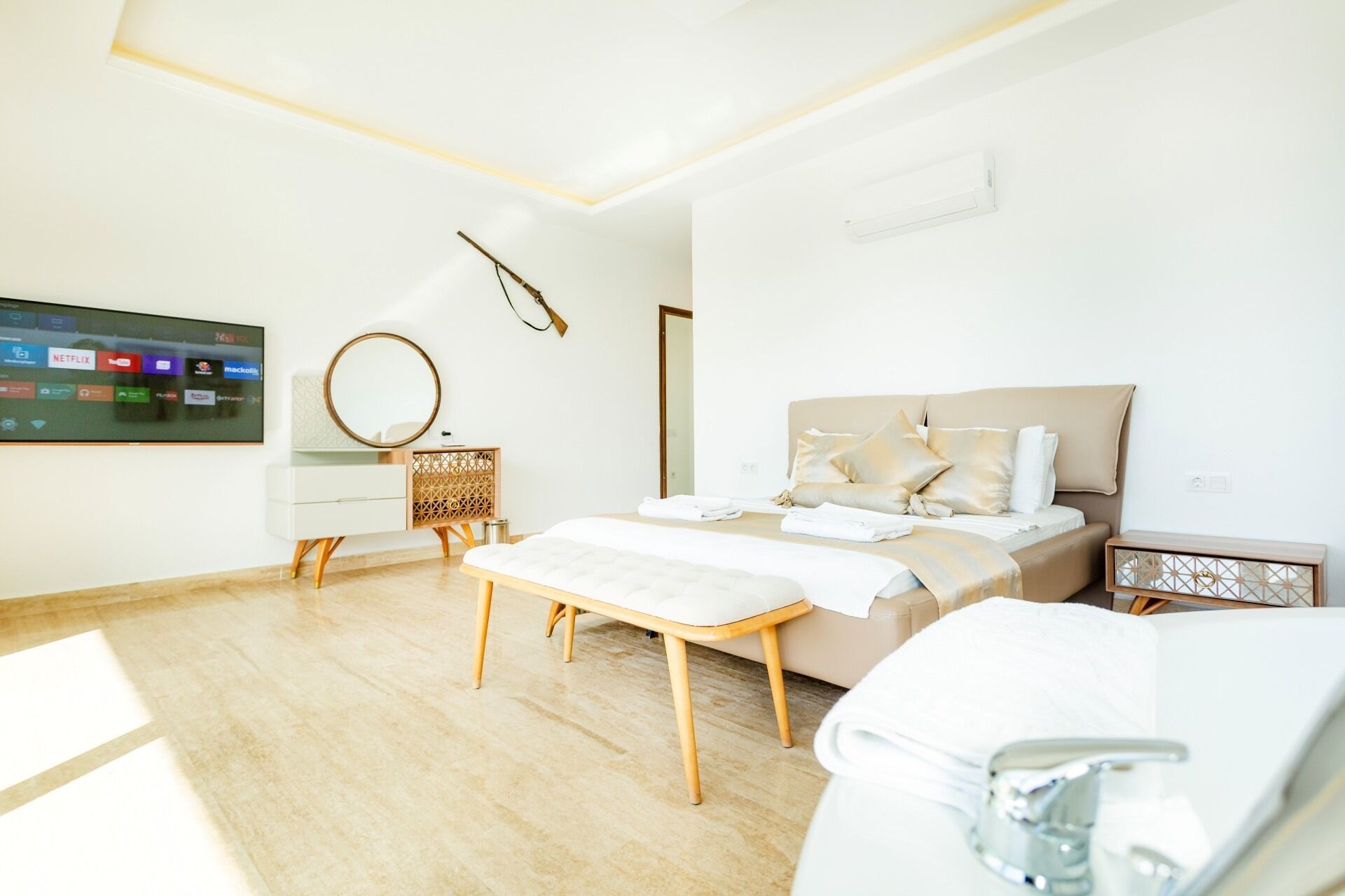 Une chambre à coucher moderne avec un lit, des tables de chevet, une télévision et un miroir.