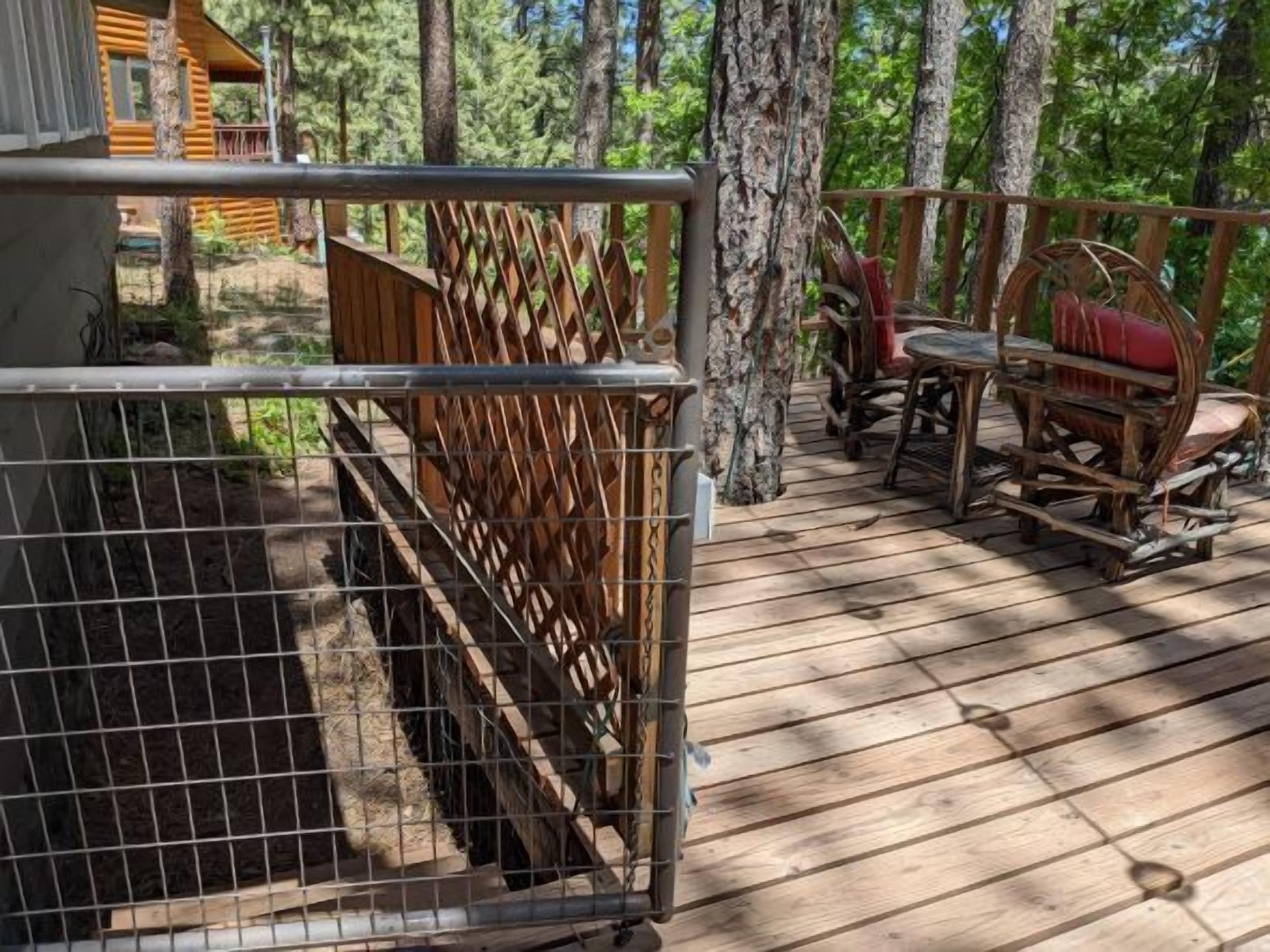 A wooden deck with a metal fence, a rustic wooden chair, and a small table.