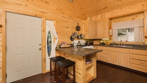 L’intérieur d’une cabane en bois comprend un coin cuisine équipé d’un poêle, d’un évier et de meubles de rangement en bois.