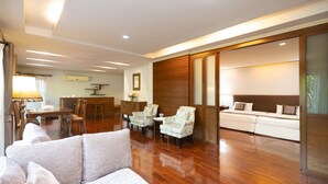 A spacious living area with a sofa, two armchairs, a dining table, and a kitchen area in the background. - Thara Cholapruek Resort (Ban Na)