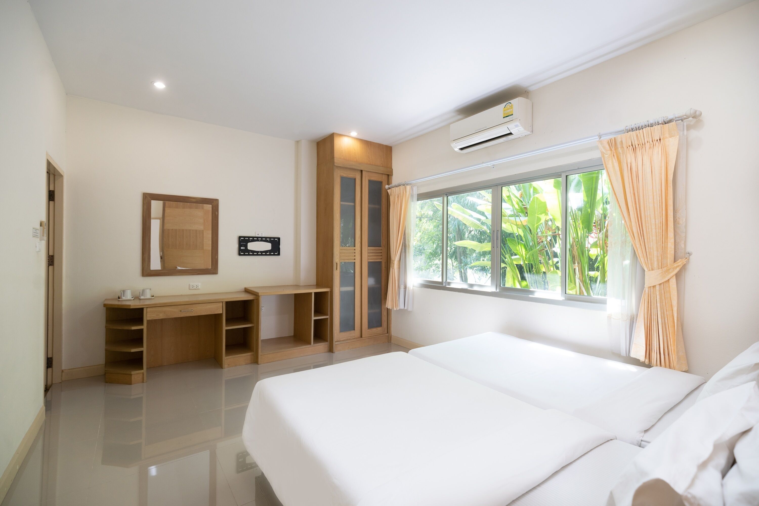Une chambre d’hôtel avec un lit, un bureau, une armoire et une fenêtre avec des rideaux.