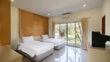 A hotel room with two beds, a TV, and a large window with curtains.