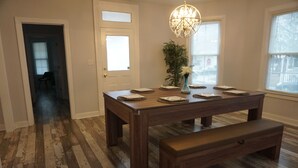 Un espace repas avec une table en bois, un banc et un lustre.