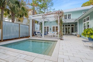 A swimming pool with a pergola and outdoor seating area.