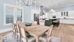 Une cuisine spacieuse avec des meubles blancs, un îlot central et un lustre.