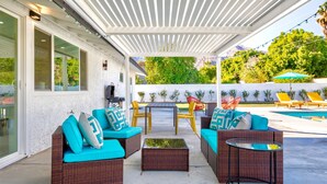 Une terrasse extérieure avec des meubles en osier, une table et une piscine.