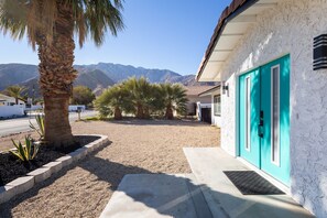 Situated in a desert landscape, this property features a stucco exterior and a vibrant door.