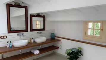 Un baño moderno con dos lavamanos, un mueble de tocador de madera, un espejo grande y una planta en maceta.