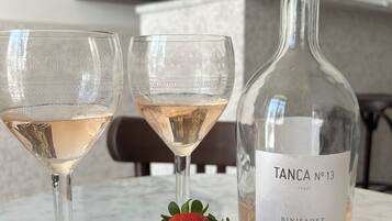 Dos copas de vino rosado, una botella de Tanca No. 13 y un bol de fresas sobre una mesa de mármol.