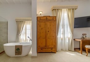 Baño con bañera independiente, armario de madera y tocador.