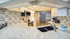 A modern kitchen with a marble countertop, stainless steel appliances, and a tiled backsplash. - Inlet Reef 618 is Recently Upgraded 2 BR 2 Ba on the beach - amazing sunset views! by RedAwning (Destin)