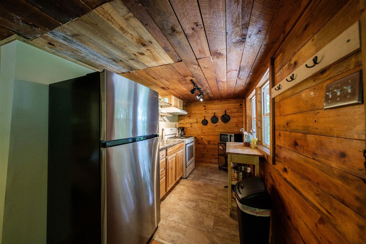 Une cuisine de taille réduite avec des murs en bois, un réfrigérateur en acier inoxydable, une cuisinière et un four à micro-ondes.