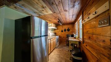 Une cuisine de taille réduite avec des murs en bois, un réfrigérateur en acier inoxydable, une cuisinière et un four à micro-ondes.