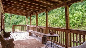A wooden deck with benches and a table, surrounded by lush greenery. - Log Cabin Getaway in the RRG. (Ravenna)