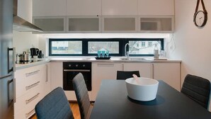 A modern kitchen with white cabinets, a black countertop, and a dining table with chairs.