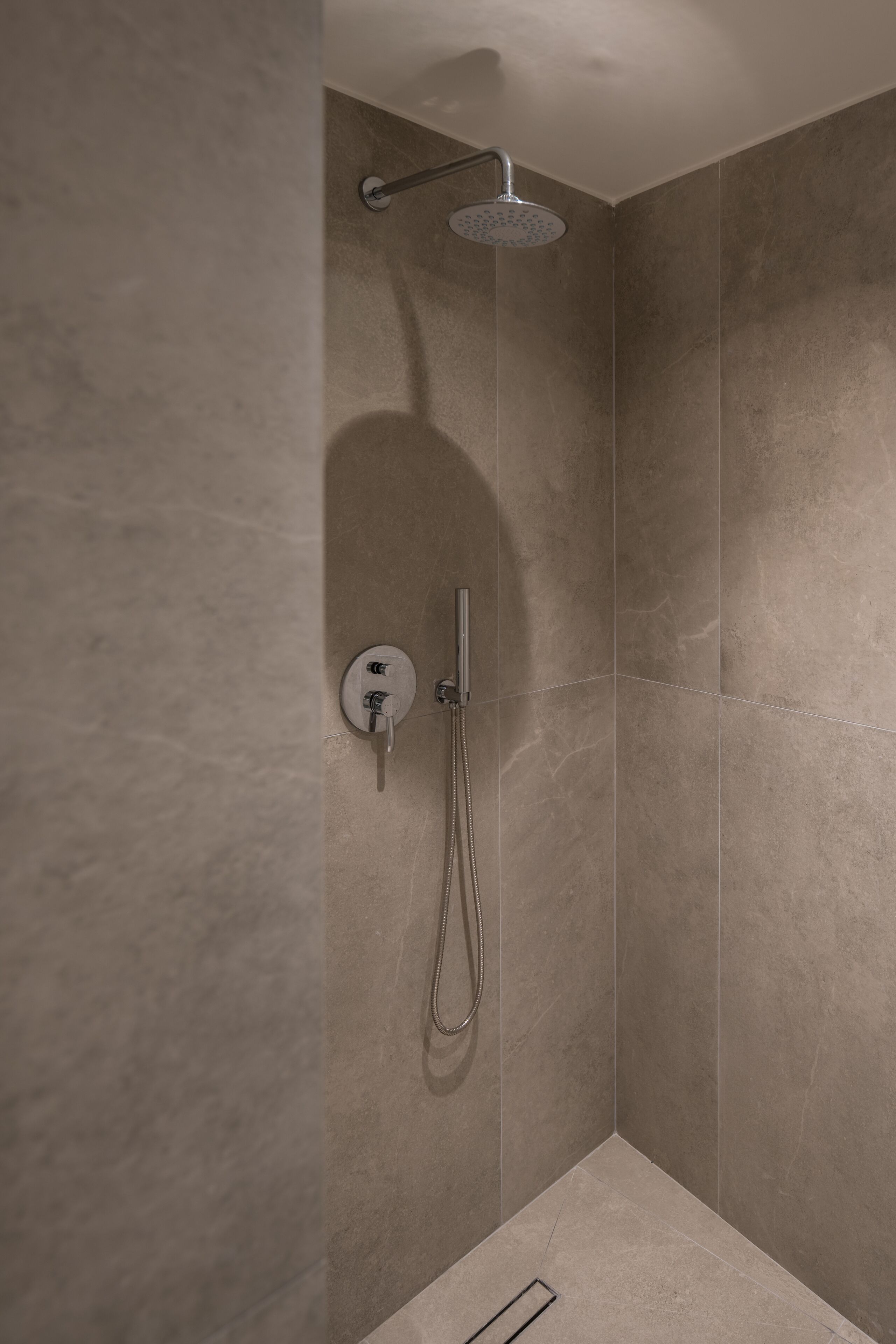 A modern shower with a handheld showerhead and a wall-mounted faucet.