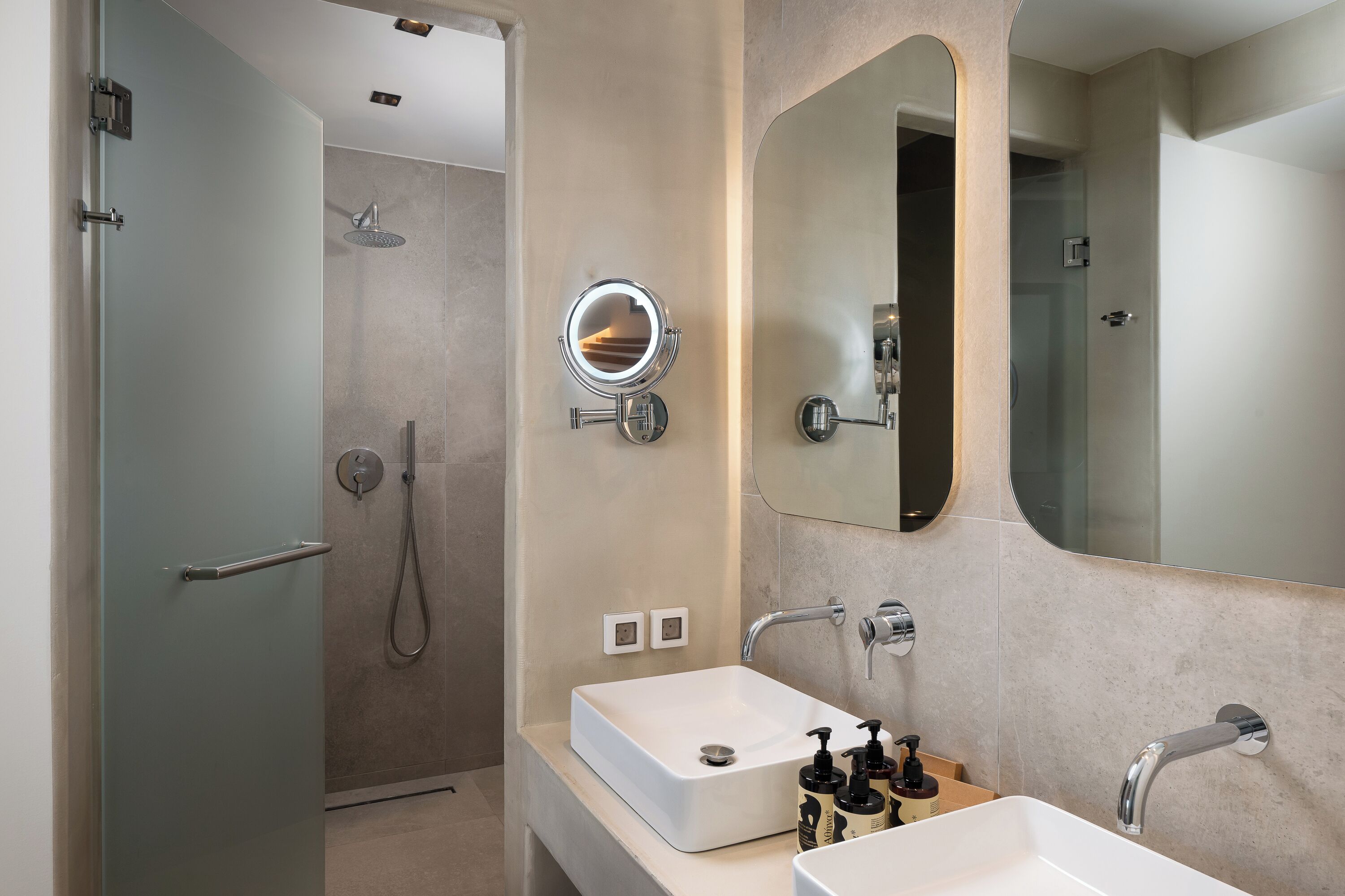 A modern bathroom with a walk-in shower, a large mirror, and a white sink.