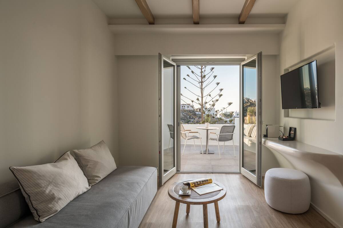 A modern living room with a sofa, a small round table, and a television mounted on the wall.