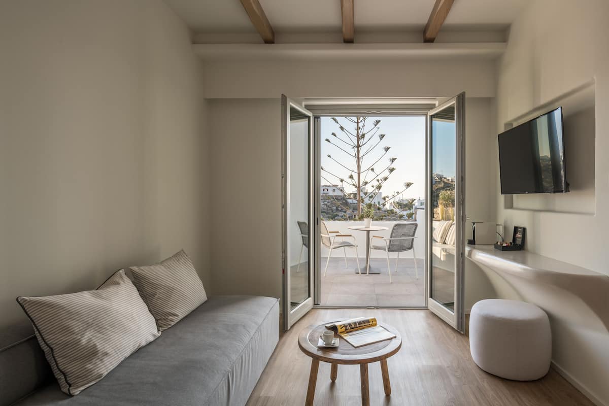 A modern living room with a sofa, a small round table, and a television mounted on the wall.