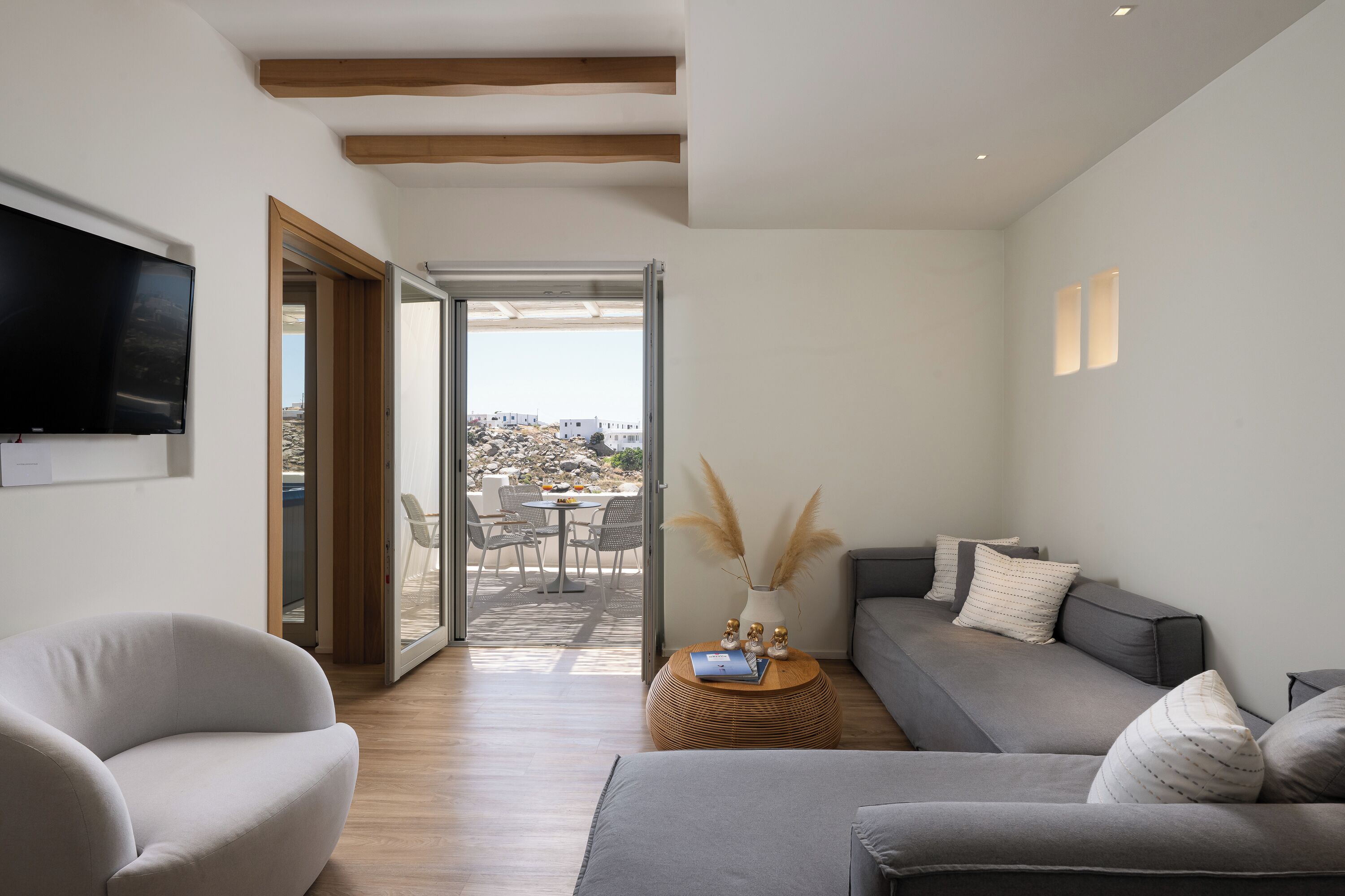 A modern living room with a sofa, armchair, and a small round table with decorative items.