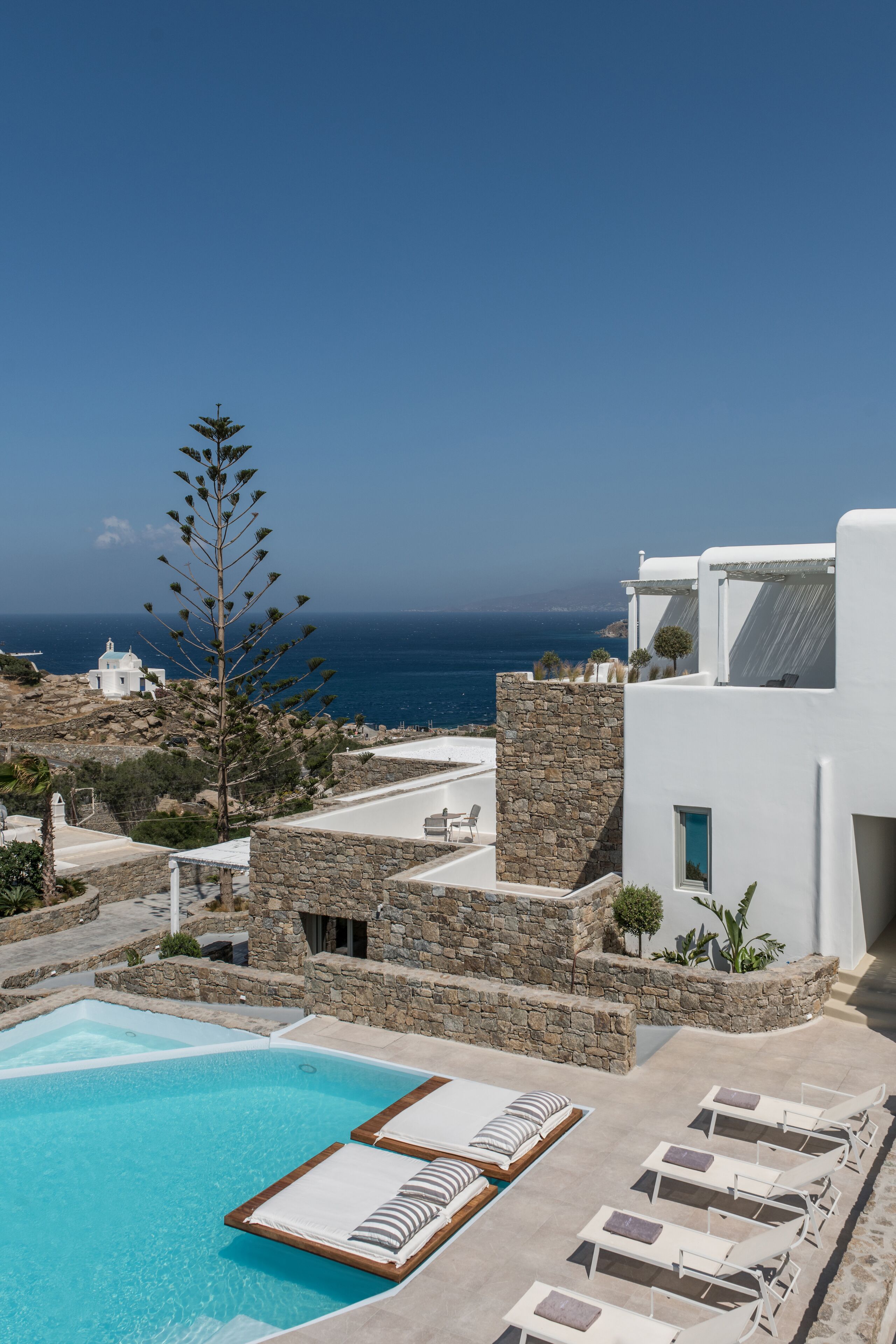 A pool area with lounge chairs and a view of the sea.