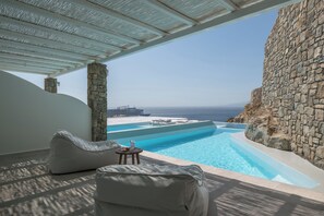 En infinitypool med fri utsikt över havet och ett kryssningsfartyg i fjärran.