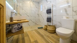 A modern bathroom with a marble-tiled wall, a wooden vanity, a white toilet, and a glass shower enclosure. - Deluxe sea view apartment (Propriano)