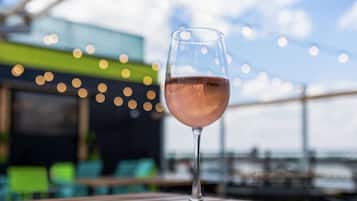 A glass of rosé wine on a wooden table with a blurred background of a restaurant or bar area.