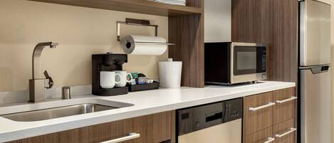 A modern kitchen with a stainless steel sink, a built-in microwave, and a refrigerator.