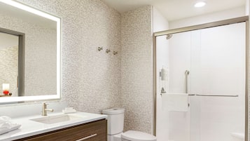 A modern bathroom with a large mirror, a sink, a toilet, and a glass shower enclosure.