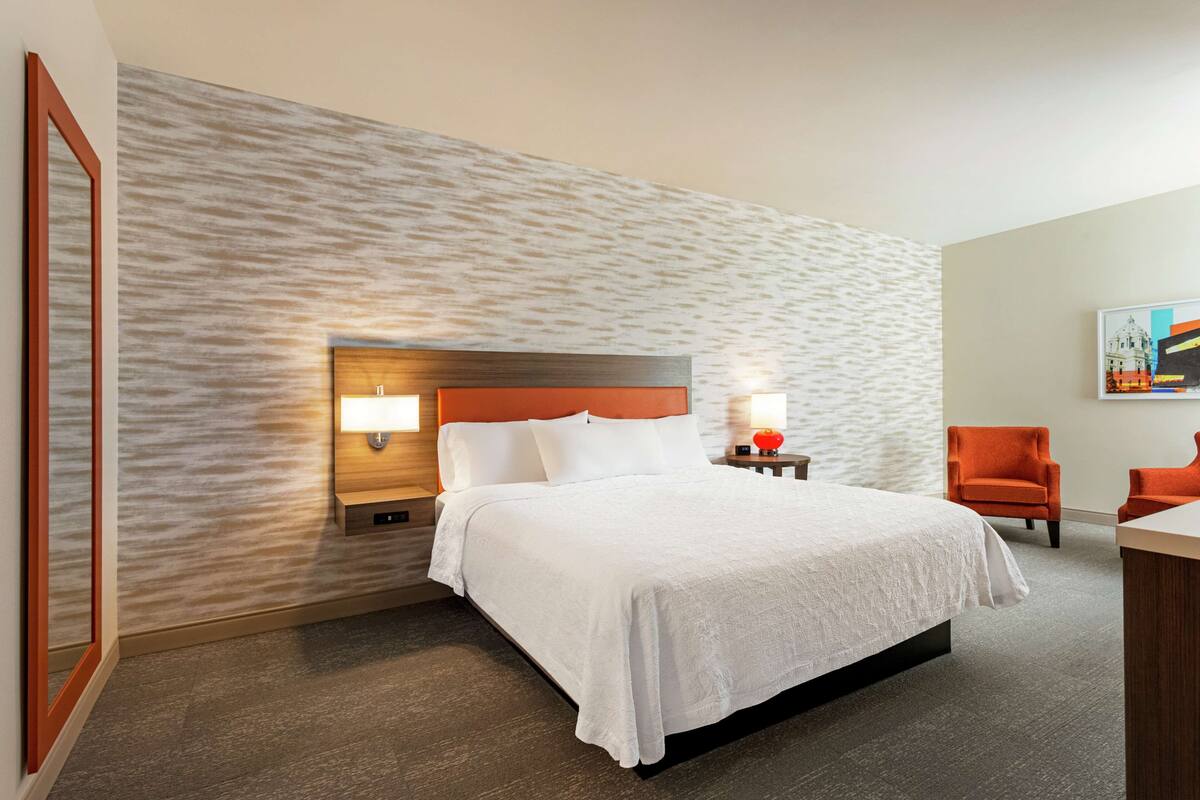 Een hotelkamer met een bed, nachtkastjes, een stoel en een bureau.