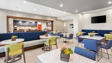 A modern restaurant with a counter, seating area, and tables.