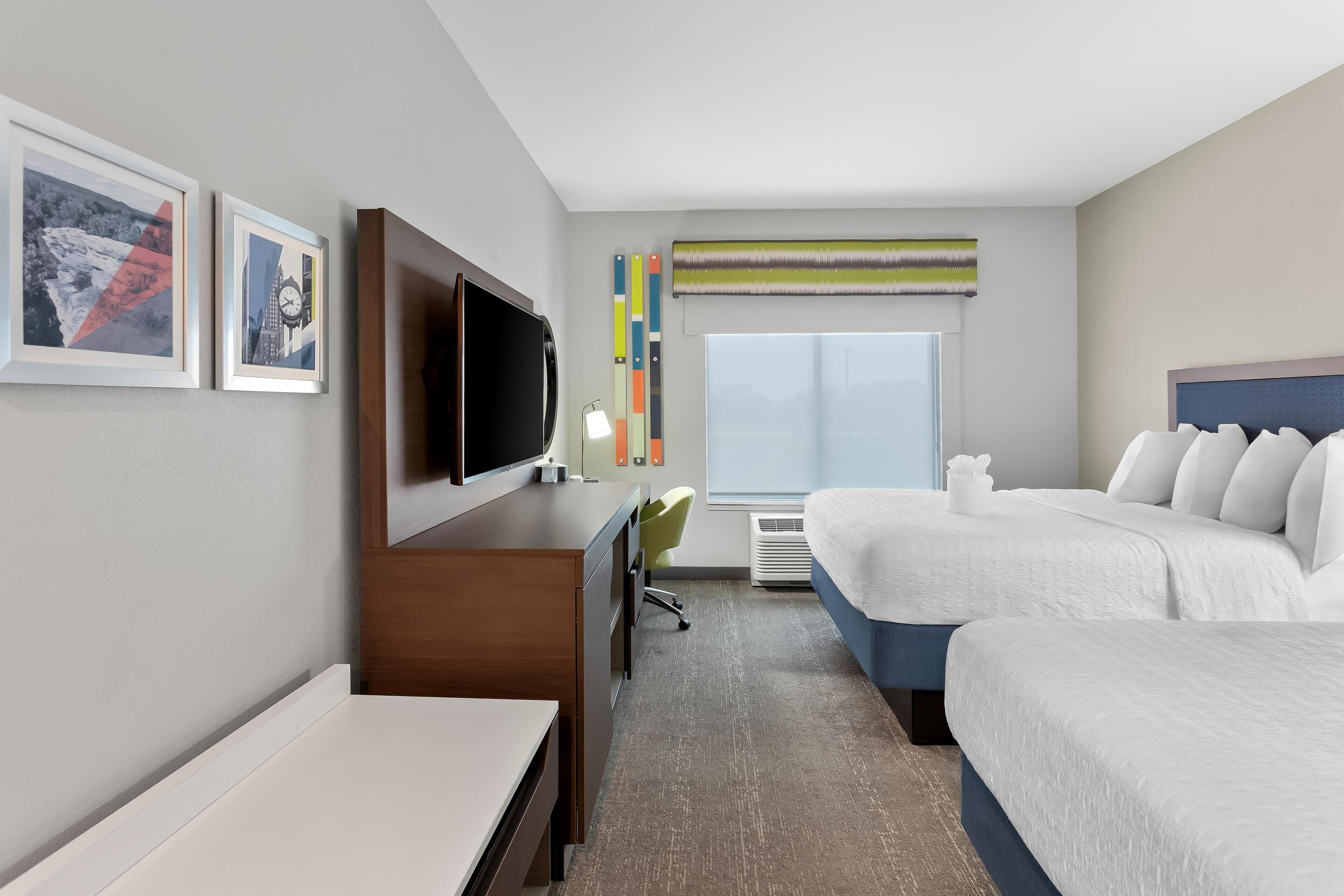 Une chambre d’hôtel équipée d’un lit, d’un bureau, d’une télévision, d’une chaise et d’une fenêtre donnant sur un paysage agréable.