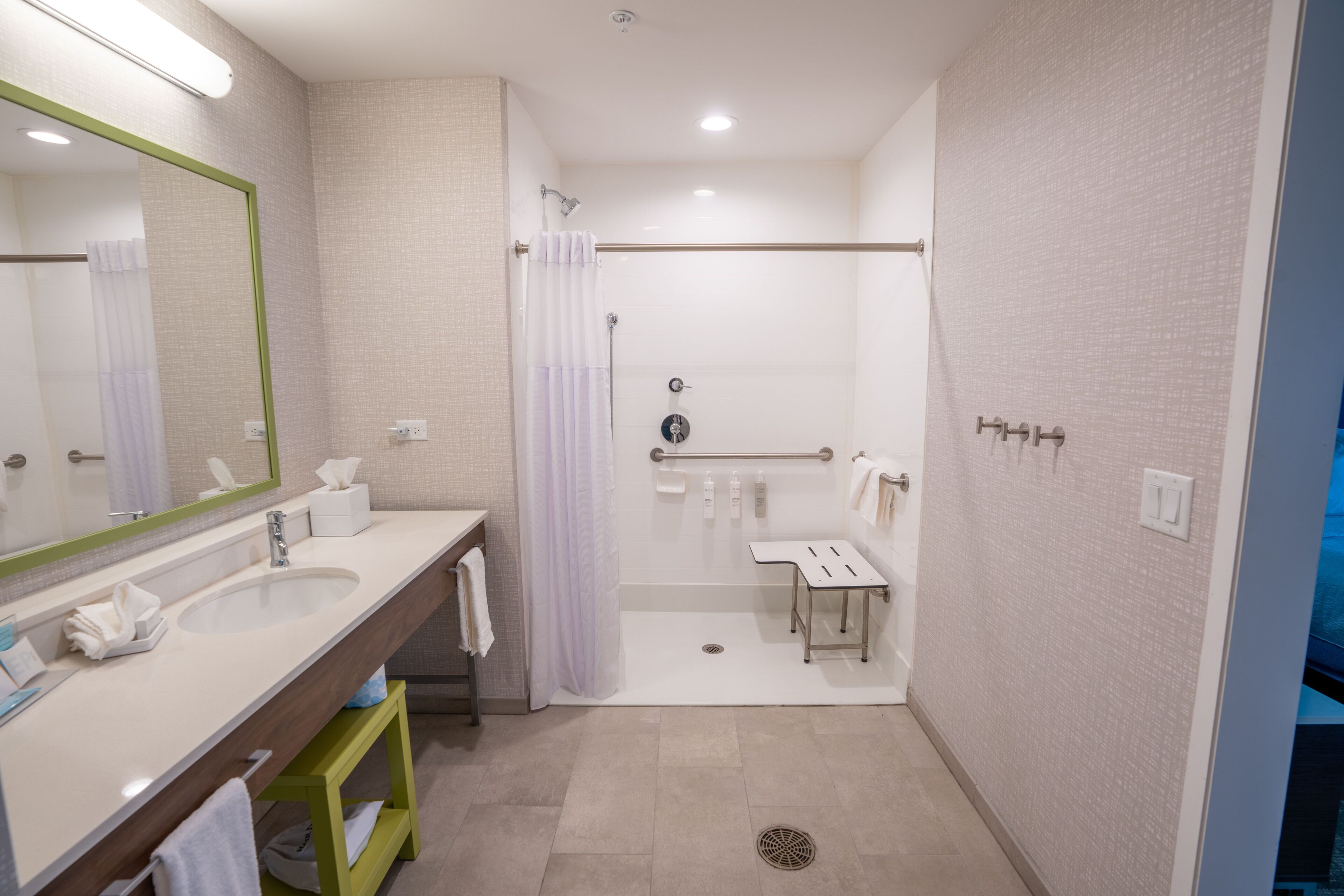 Een moderne badkamer met twee wastafels, een douche en een toilet.