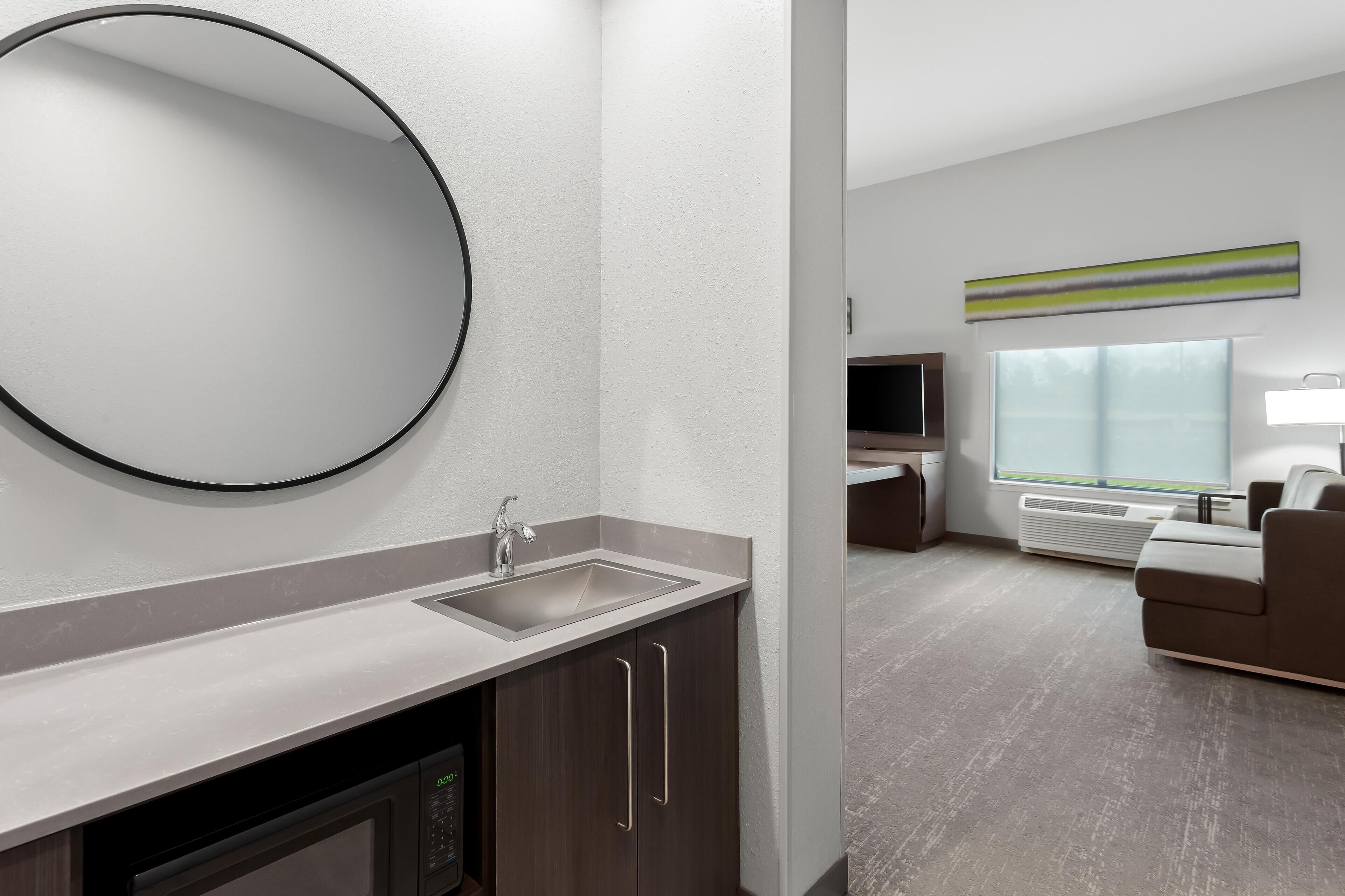 A modern bathroom with a sink, mirror, and cabinet.