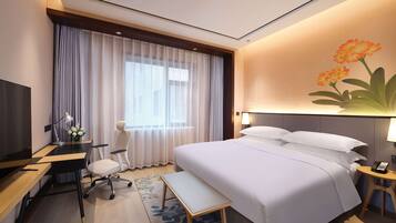 Habitación de hotel con cama, escritorio, silla y televisor.