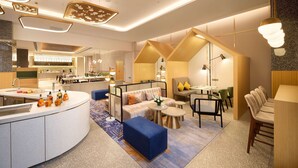 Una hall moderna di un hotel con un'area salotto centrale, una cucina e una sala da pranzo.