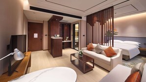 Una camera d'hotel moderna con divano, tavolino, televisore e letto.