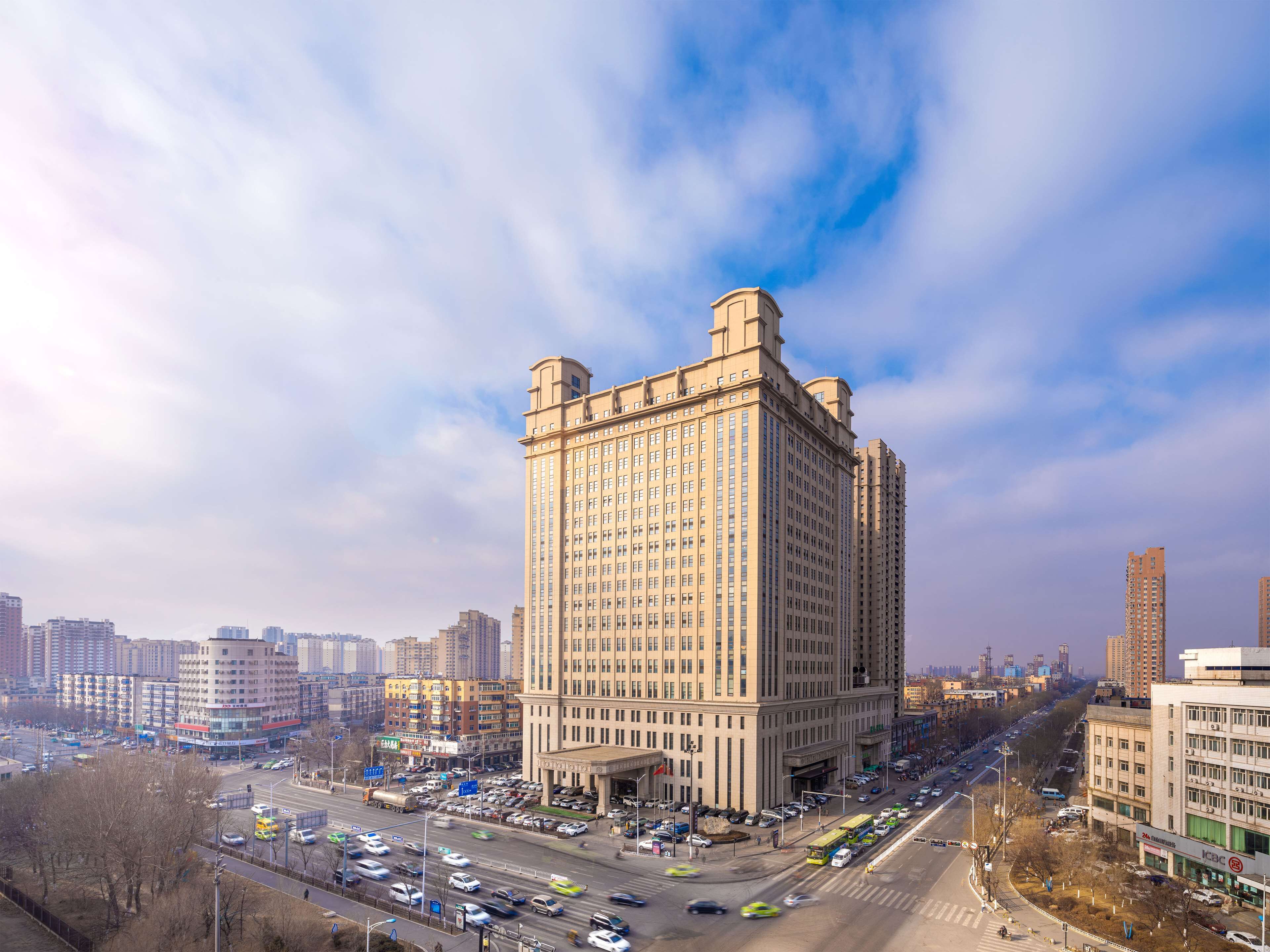 A high-rise building with a classic architectural style, surrounded by a busy urban street with vehicles and other buildings.