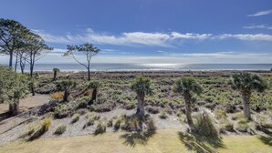 Ett kustlandskap med gles vegetation, en klar himmel och utsikt över havet.