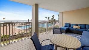 Uma varanda com vista para a piscina, um sofá e uma mesa.