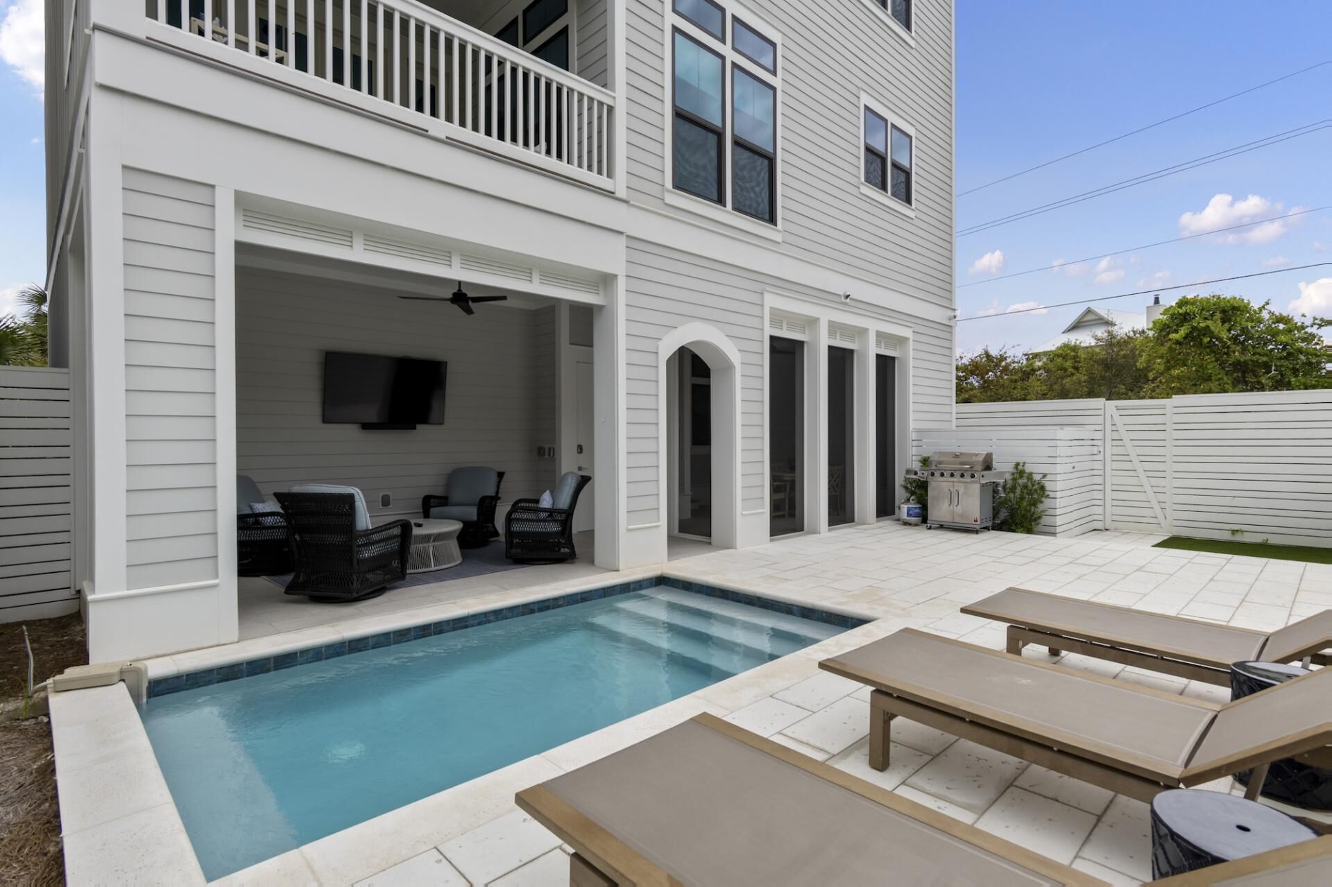 A two-story house with a backyard pool, outdoor seating, and a barbecue grill.