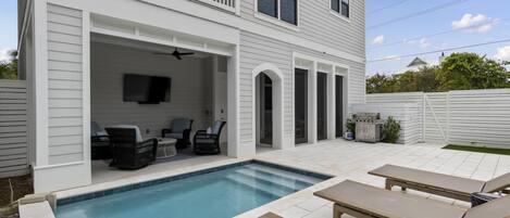 A two-story house with a backyard pool, outdoor seating, and a barbecue grill.