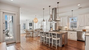 A modern kitchen with a central island, white cabinetry, and a large stainless steel range hood.