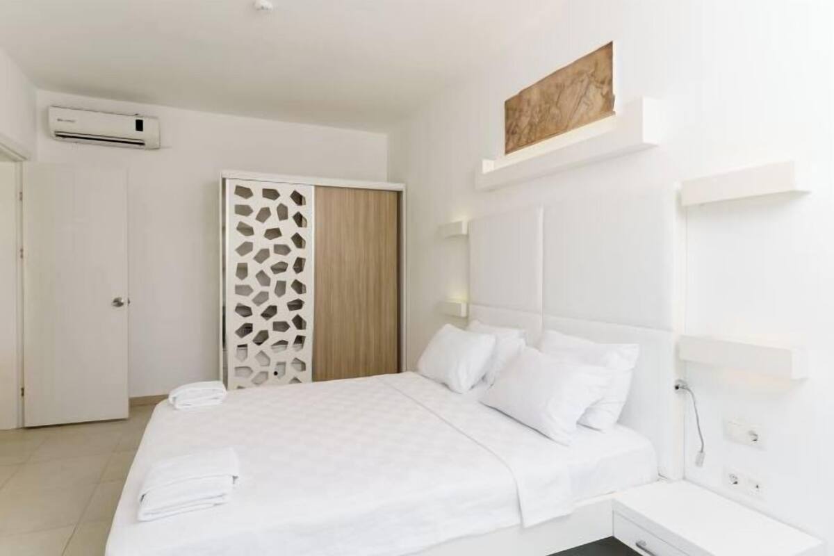 Una habitación de hotel moderna con cama, mesita de noche y un panel decorativo en la pared.